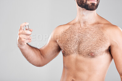 Buy stock photo Cologne, perfume and man with spray bottle in an isolated gray background studio. Cosmetic, luxury and body care product with a male model holding a fragrance in hands spraying his chest with mockup