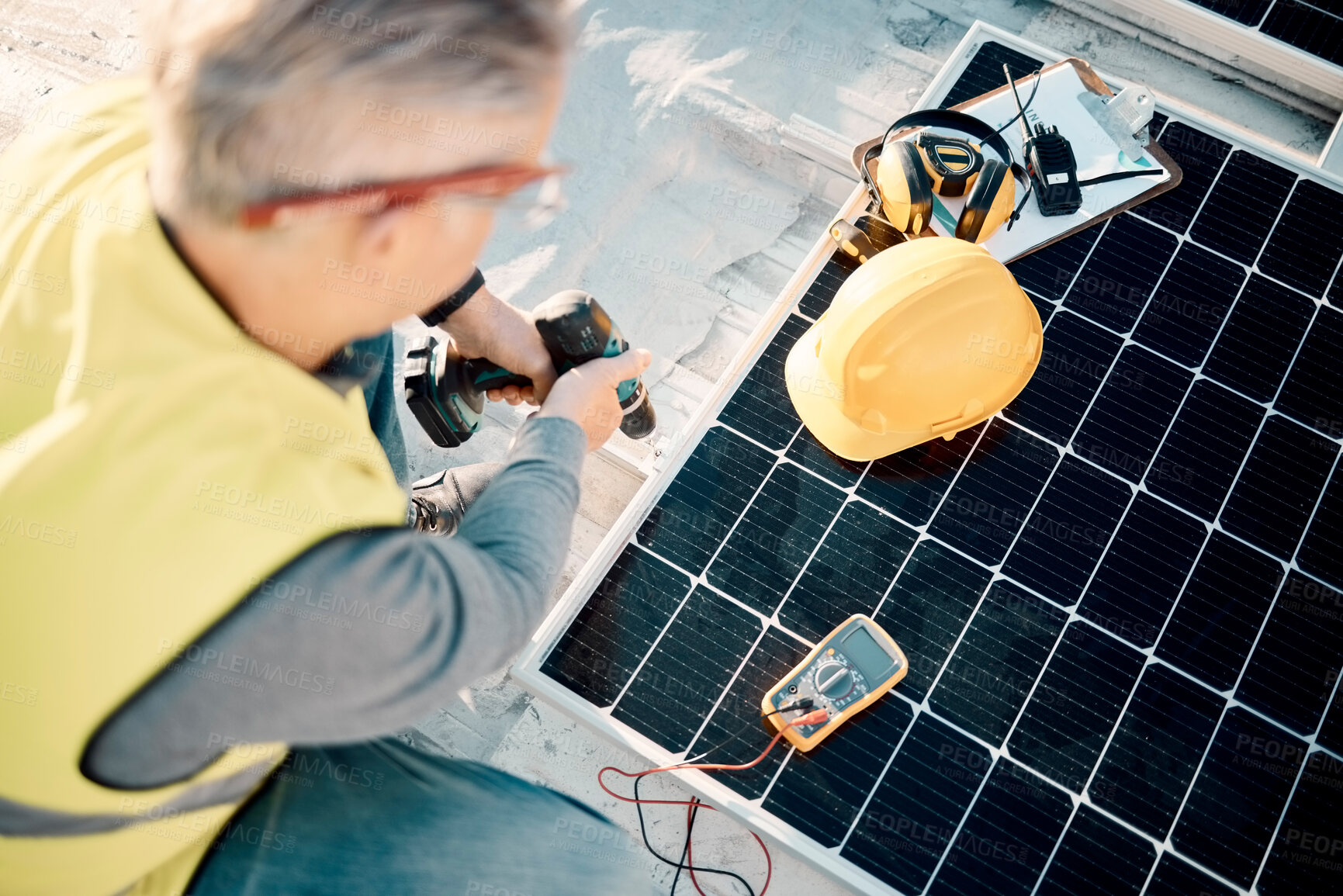 Buy stock photo Solar energy, industrial work and senior construction worker on a building roof with panel. Sustainability, electricity and industrial grid with a mature engineer drilling with tools outdoor
