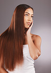 Woman, long hair and face for skincare, beauty or cosmetics against a gray studio background. Attractive female touching skin in satisfaction for self love or facial, haircare and cosmetic treatment