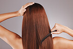 Beauty, comb and woman doing haircare in a studio with a brazilian, keratin or botox treatment. Health, hygiene and back of female model with a long, healthy and shiny hair style by a gray background