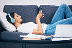 Headphones, sofa and woman student on study break for mental health, relax podcast and music streaming services. Smartphone, listening to audio and young person on couch with calm mindset or wellness