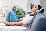 Music, relax and quiet with a woman in her home, listening to the radio while sitting on the living room sofa. Peace, wellness or headphones with an attractive young female streaming audio in a house