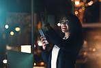 Business woman, phone and night in the office with bokeh lights to work late for project deadline. African American female employee working overtime with smartphone technology in a dark workplace