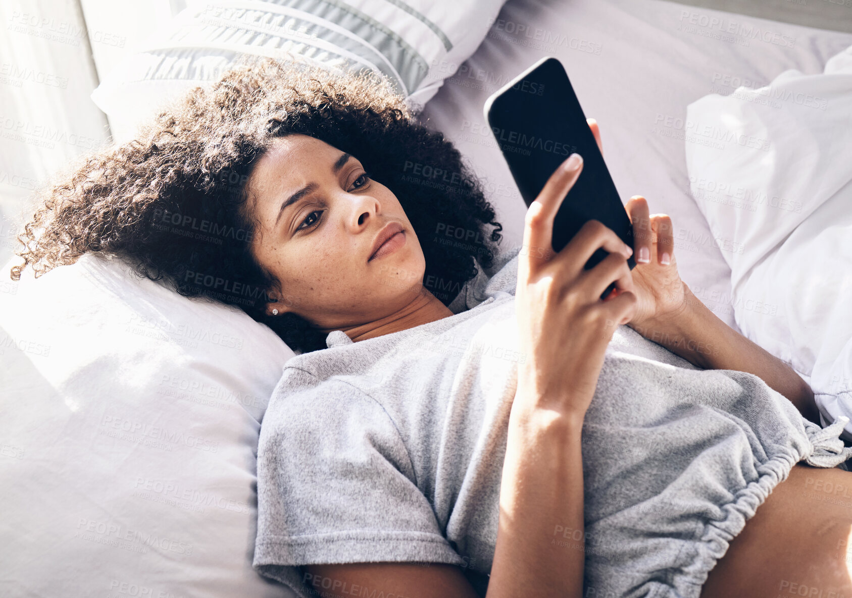 Buy stock photo Black woman, sad and typing with phone on bed in home bedroom for social media or internet browsing in the morning. Technology, bored and lonely female with mobile for web scrolling or networking.