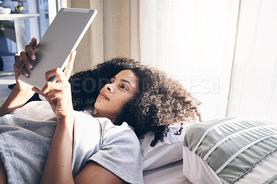 Buy stock photo Tablet, black woman and relax in bed in bedroom for social media, texting or internet browsing in the morning. Technology, home and female with digital touchscreen for web scrolling after waking up.