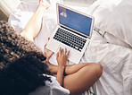 Top view, bed and woman browsing on a laptop for social media or the internet in the morning. Technology, bedroom and female remote freelancer working on a freelance project on a computer at home.