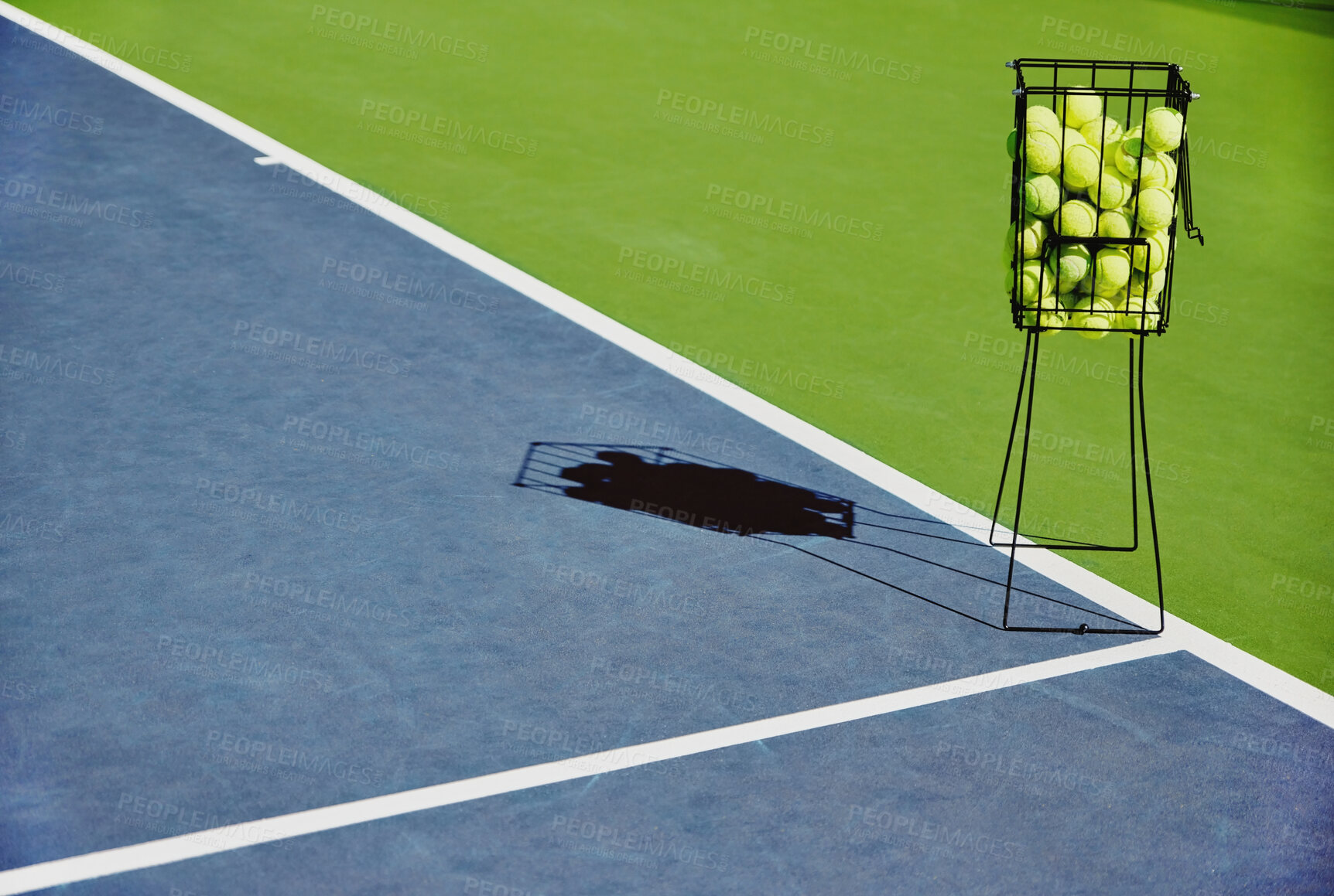 Buy stock photo Tennis, sport balls and basket of sports equipment on a training court outdoor with no people. Exercise, fitness and workout equipment shadow for match of game competition on turf ground in summer