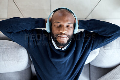 Buy stock photo Top view, music headphones and black man on sofa in home living room streaming audio. Meditation, relax technology and male on couch in lounge listening to peaceful podcast, radio or sound in house.