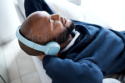 Buy stock photo Music headphones, top view and black man on sofa in home living room streaming audio album. Relax, technology and happy male on couch in lounge listening to fun podcast, radio or sound in house.