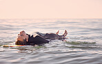 Surfing, woman and lying on board in waves, sea and ocean for summer adventure, freedom and sky background. Calm female surfer relax in water, beach and swimming for tropical holiday, travel or peace