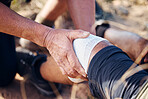 Sport bandage, first aid and hands of medical support for knee pain of elderly man hiking in mountain. Exercise, fitness and paramedic in nature with senior athlete hurt from sports accident outdoor