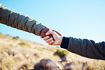 Friendship, help and men holding hands on a hike for support while climbing a rock on a mountain. Assistance, adventure and interracial male friends trekking together for fitness challenge in nature.