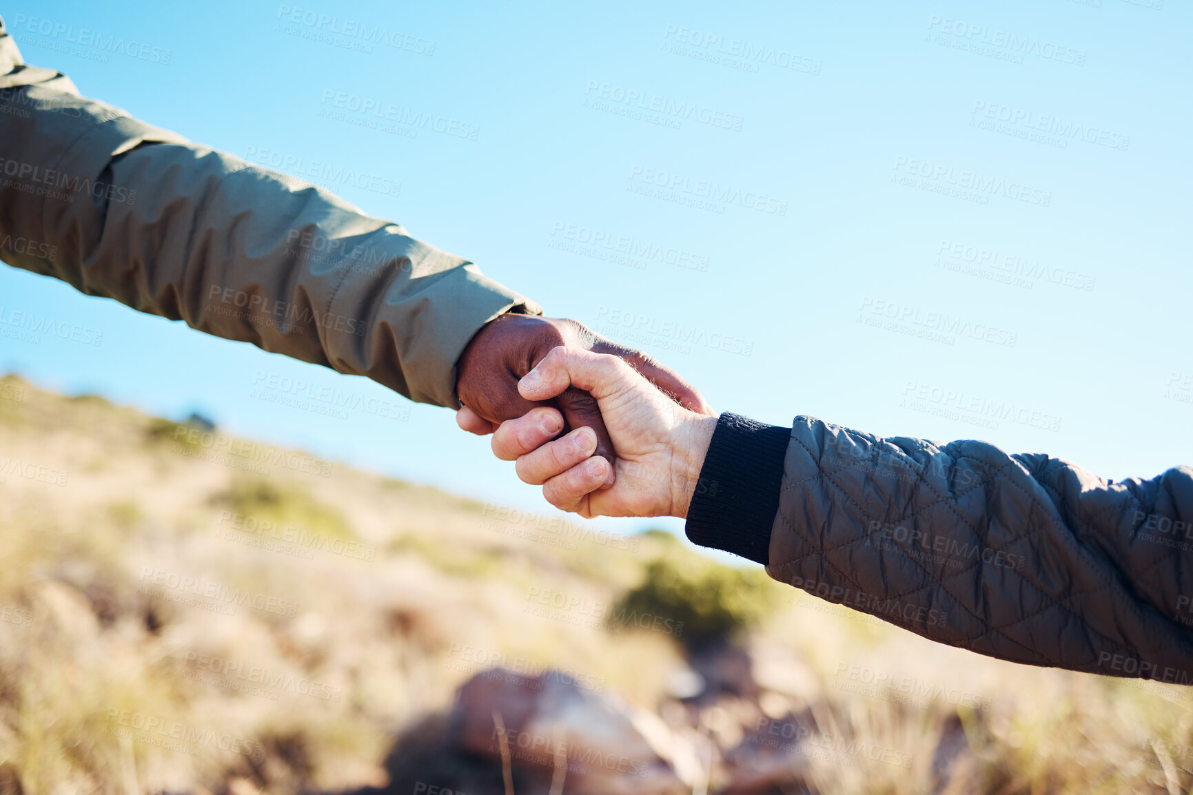 Buy stock photo Friendship, help and men holding hands on a hike for support while climbing a rock on a mountain. Assistance, adventure and interracial male friends trekking together for fitness challenge in nature.