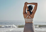 Back, stretching and woman and a beach for yoga, fitness and cardio on ocean background. Rear view, arm and stretch for girl during meditation, exercise and workout at the sea for wellness and peace