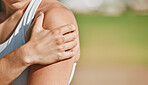 Hand, arm or injury with a sports woman holding her shoulder in pain outdoor next to mockup space. Fitness, medical and anatomy with a female athlete suffering with an injured joint or muscle outside