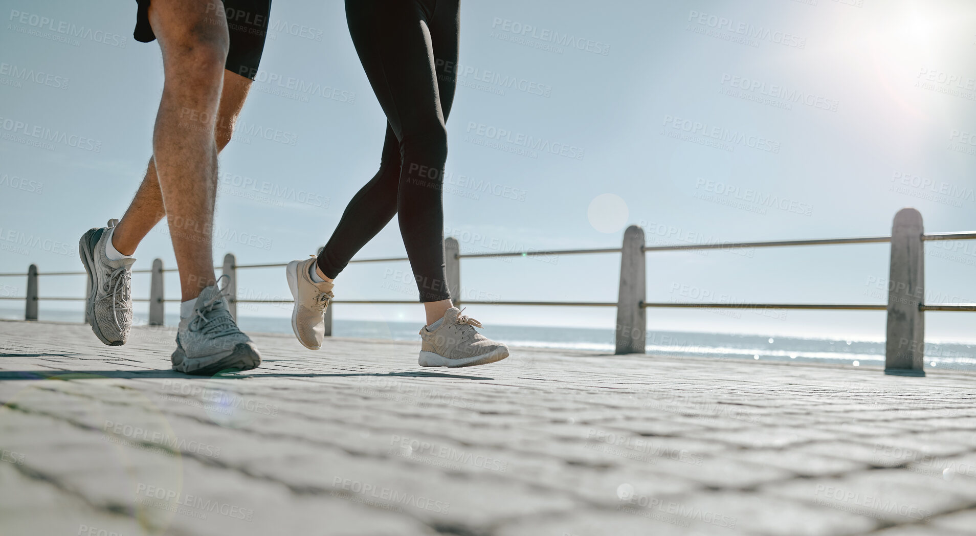 Buy stock photo People, legs and running at the beach for exercise, cardio workout or training together outdoors. Leg of friends taking run, walk or jog on warm sunny day by the ocean coast for healthy wellness