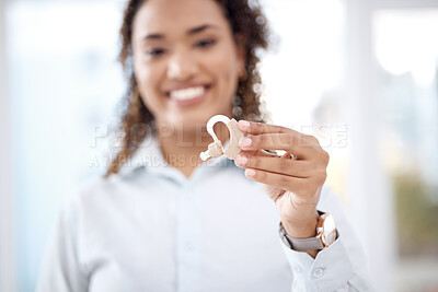 Buy stock photo Hand, hearing aid and insurance with a black woman holding a listening device in a healthcare clinic. Medical, technology and audiology with a female medicine professional standing in a hopsital