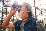 Hiking, binoculars and senior man in nature looking at view, sightseeing or watching. Binocular, adventure and elderly male with field glasses, trekking or exploring on holiday or vacation outdoors.