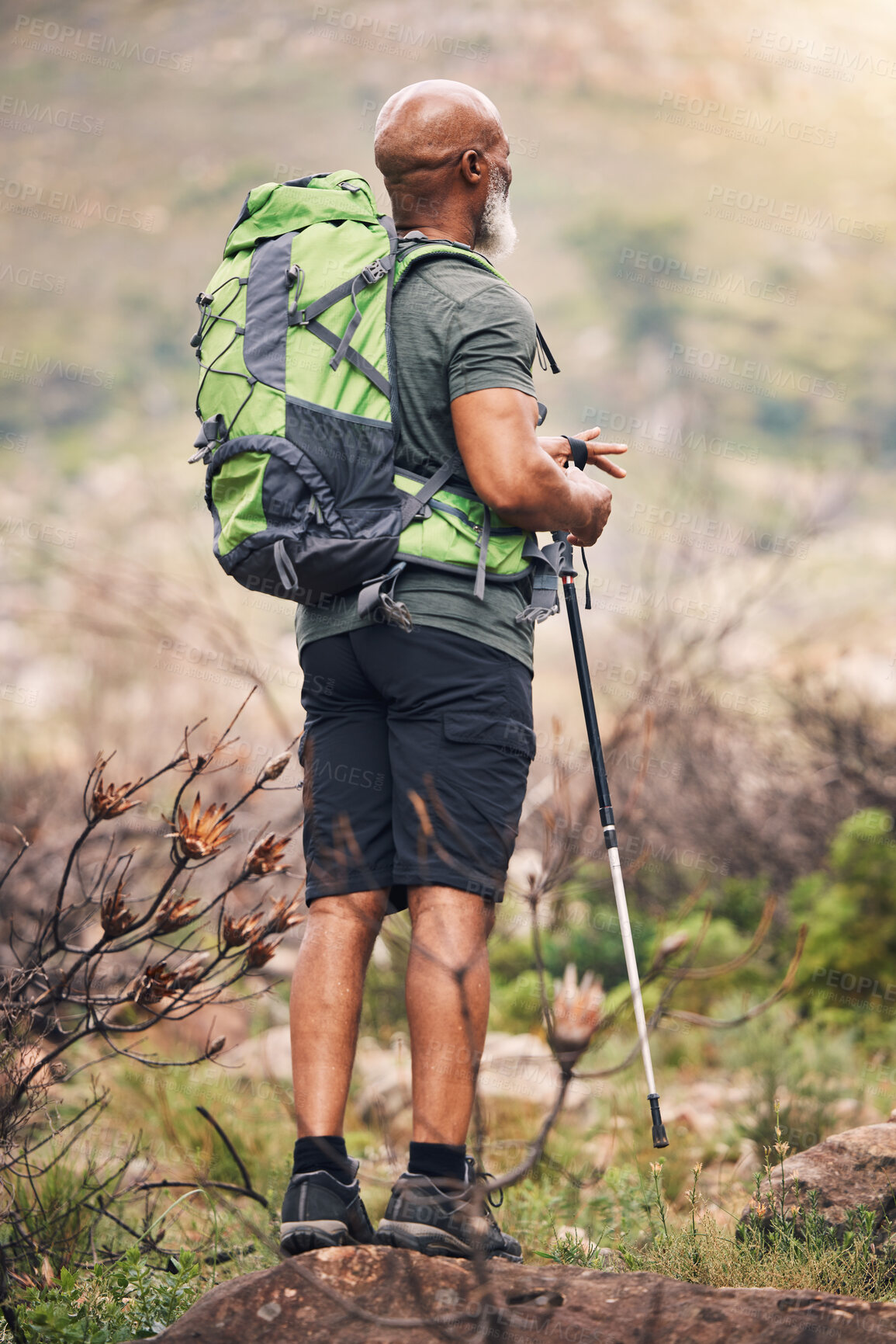 Buy stock photo Black man, hiking and mountain with backpack for travel, adventure or trekking in the nature. African American male hiker with stick standing on rock for traveling or backpacking in the outdoors