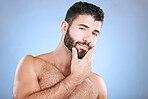 Portrait of man with hand on beard, confident face and morning cleaning treatment isolated on blue background. Facial hygiene, male model beauty and grooming health, wellness and skincare in studio.