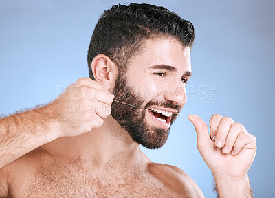 Buy stock photo Oral, floss and dental hygiene with a man in studio on a blue background cleaning his teeth for healthy gums. Dentist, healthcare and mouth with a young male flossing to remove plaque or gingivitis