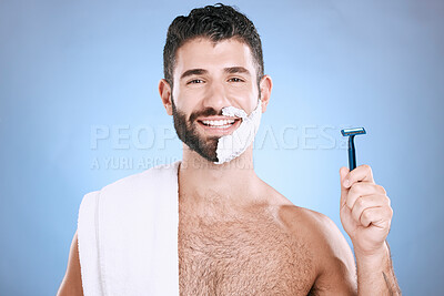 Buy stock photo Portrait of happy man with foam on beard, razor and towel in skin product placement in studio mock up. Shaving cream on face, smile and hair or skincare for male model, isolated on blue background.