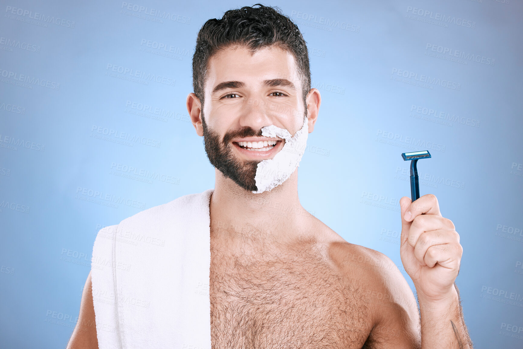 Buy stock photo Portrait of happy man with foam on beard, razor and towel in skin product placement in studio mock up. Shaving cream on face, smile and hair or skincare for male model, isolated on blue background.