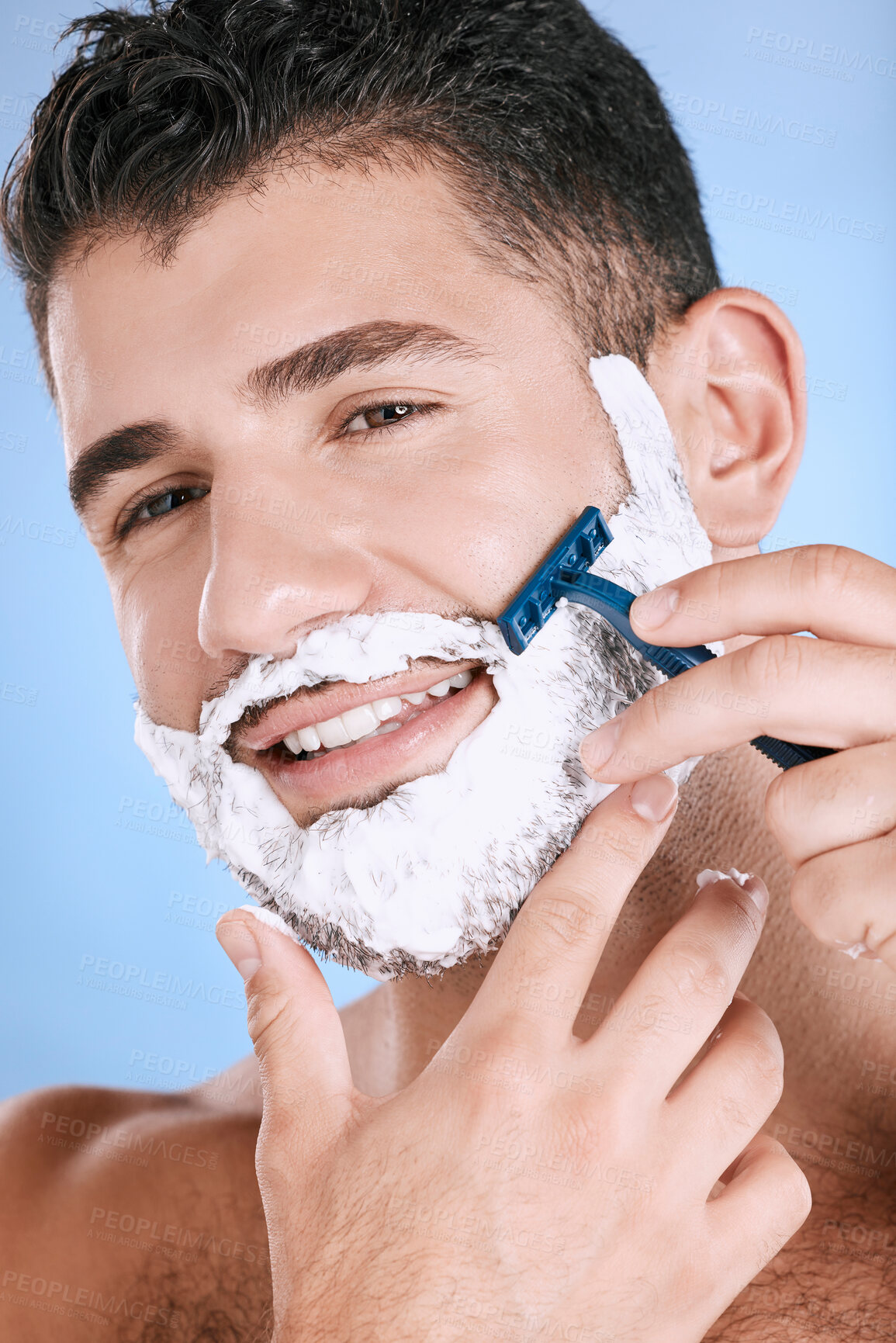 Buy stock photo Smile, foam and man with beard shaving with razor in hand, facial and product placement in studio mock up. Shave cream on face, hair and skincare for happy male model isolated on blue background.
