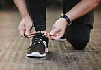Fitness, hands and tie shoes in gym to start workout, training or exercise for wellness. Sports, athlete and man tying sneakers or footwear laces to get ready for exercising or running for health.