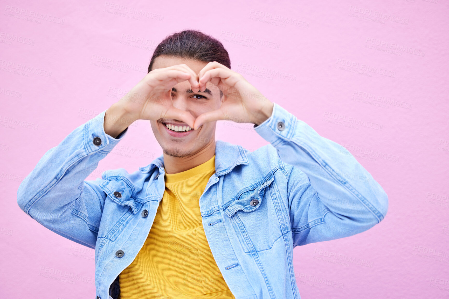 Buy stock photo Portrait, heart and valentines day with a man outdoor on a pink wall background for love or romance. Hand sign, romantic and gesture with a loving person showing affection against pastel color