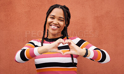 Buy stock photo Heart shape, portrait and black woman by a wall in the city while on a walk on a vacation. Happy, smile and beautiful African female with love hand gesture in a town while on holiday or weekend trip.