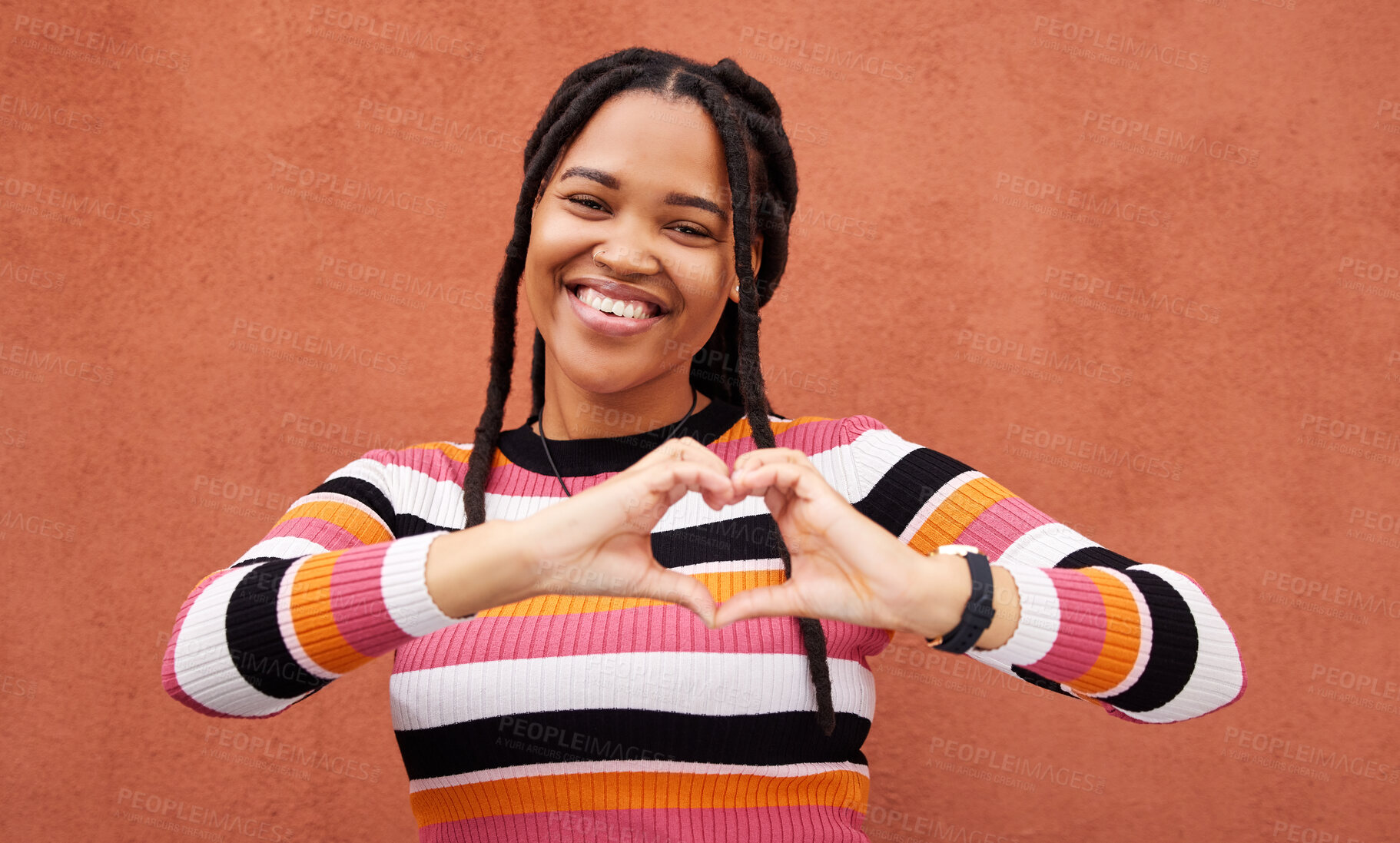 Buy stock photo Heart shape, portrait and black woman by a wall in the city while on a walk on a vacation. Happy, smile and beautiful African female with love hand gesture in a town while on holiday or weekend trip.
