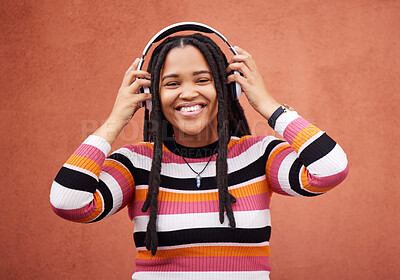 Buy stock photo Wall, portrait and black woman with headphones, smile and carefree with music, streaming and joyful. Face, Jamaican and female with headset for audio, sounds and chilling with happiness and relax