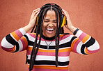 Black woman, music headphones and happiness by wall in city for walk, adventure and comedy album. Young gen z girl, audio streaming and listen to comic podcast on website, radio and happy in metro
