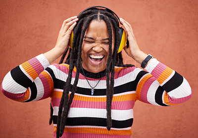 Buy stock photo Black woman, music headphones and happiness by wall in city for walk, adventure and comedy album. Young gen z girl, audio streaming and listen to comic podcast on website, radio and happy in metro