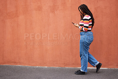 Buy stock photo Black woman walking with smartphone in city, outdoor with technology, chat and communication with travel and fashion. Social media, urban street and wall with mockup and 5g, female in Jamaica