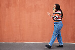 Mockup, phone call and black woman in a city street against orange background for advertising. Walking, talking and girl speaking on copy space outdoor for relax, trip and social network on space