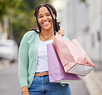 Fashion, portrait or happy black woman shopping with a smile walking on city street in retail therapy. Freedom, relax or African gen z girl with clothes, gift or products on discounted sales offer