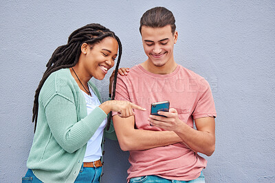 Buy stock photo Man, woman and phone by wall for meme, social media or blog post with happiness together in city. Interracial couple, smartphone and happy with smile, comic and funny video on internet app in metro