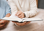 Hands, bible and prayer with a senior couple reading a book together in their home during retirement. Jesus, faith or belief with a man and woman praying to god in their house for spiritual bonding