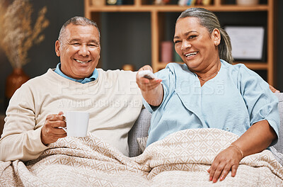 Buy stock photo Coffee, relax and old couple watching tv with blanket on sofa in home living room laughing at comic film. Retirement portrait, valentines love and happy elderly man and woman streaming on television.