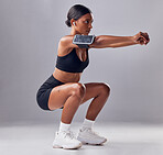 Black woman, studio background and squat training for fitness, smartphone and strong legs, muscle or mind. Gen z girl, personal trainer and phone with vision, motivation or mindset for anatomy goal