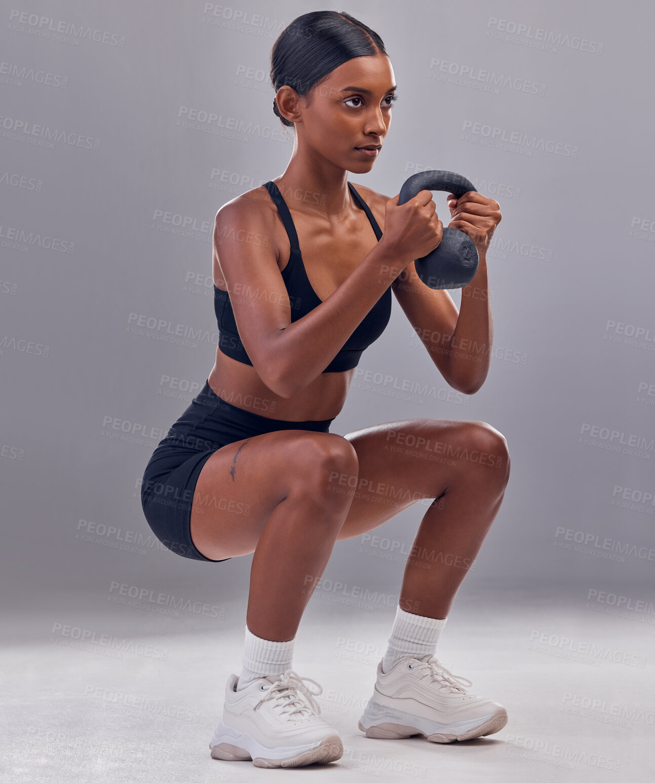 Buy stock photo Woman, kettlebell squats and exercise in studio for fitness, sports workout and focus wellness mindset. Strong female, bodybuilder or weights training for muscle power, energy or health on background