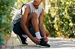 Fitness, running and tying shoes of black man in nature and  ready for cardio, jogging or workout. Training, exercise and health with runner and tie laces on ground for sports, wellness or motivation