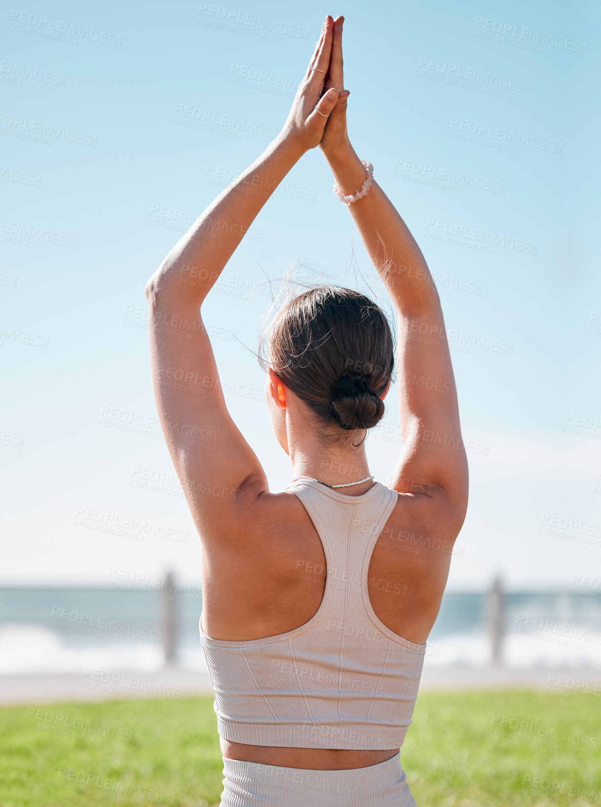 Buy stock photo Fitness, woman and yoga on grass by beach for spiritual wellness, exercise or meditation in nature. Sporty female yogi back in warm up arm stretch for zen workout, relax or meditating in the outdoors