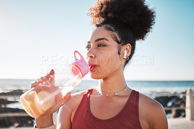 Buy stock photo Fitness black woman drinking water on beach for exercise, listening to music and cardio training in blue sky lens flare.  Liquid bottle for diet, goals and tired sports runner or USA person by ocean