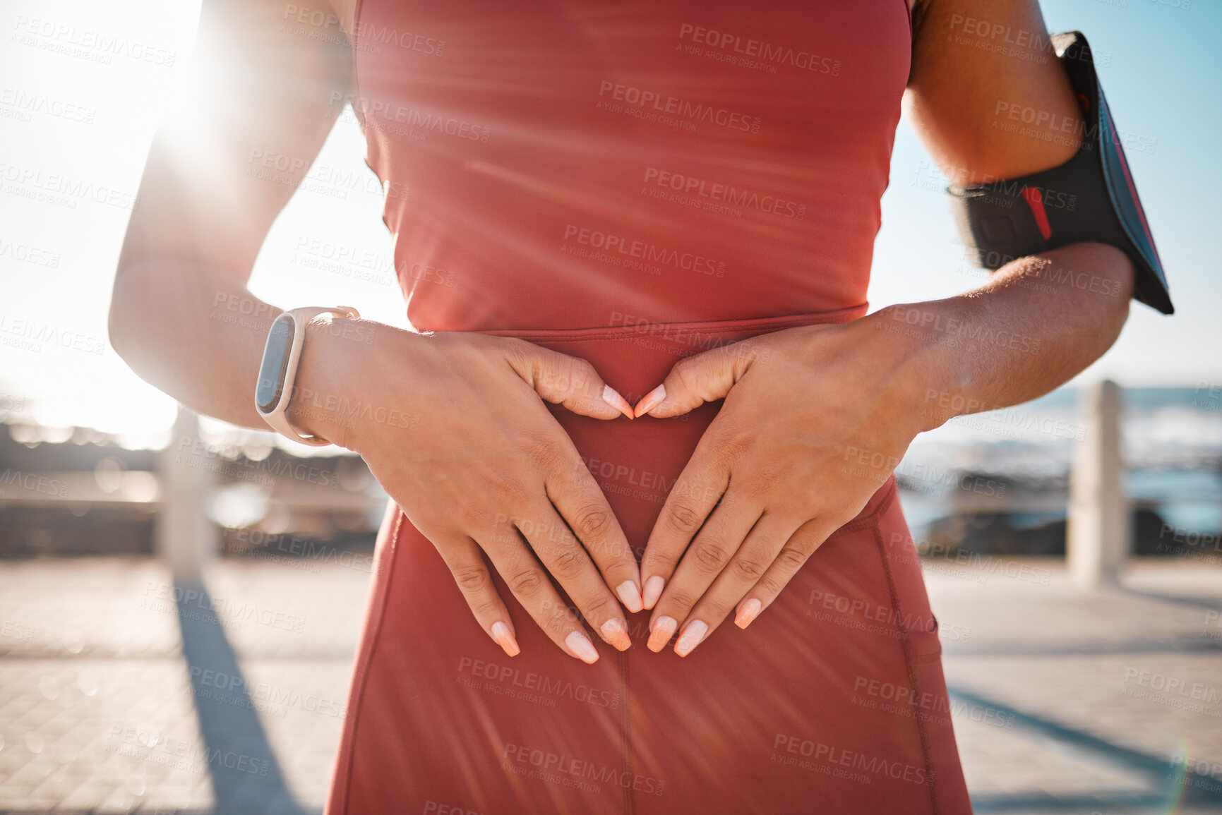 Buy stock photo Heart hands, fitness runner and black woman by the sea with emoji hand sign for exercise. Workout, running training and athlete outdoor in the summer sun and loving gesture on stomach for self love 