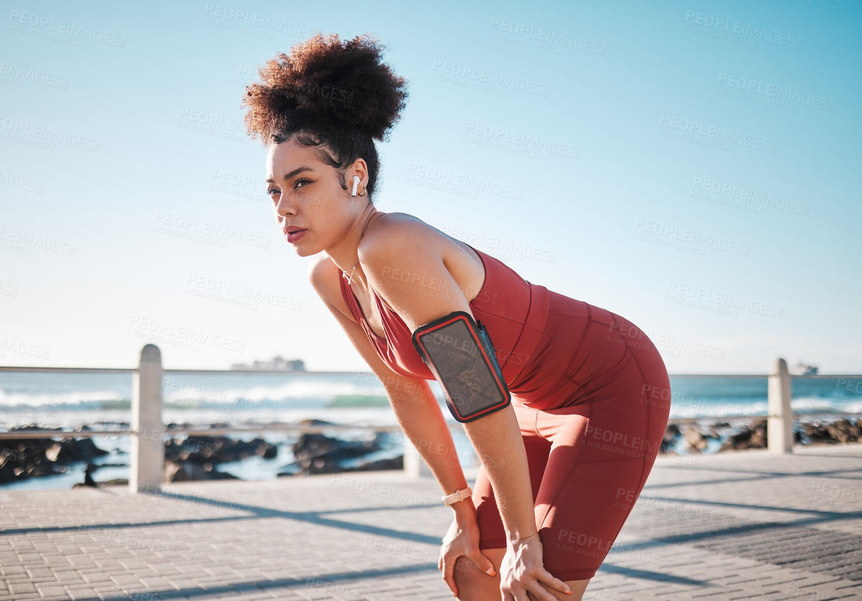 Buy stock photo Fitness, music and exhausted with a black woman runner on the promenade for cardio or endurance training. Exercise, running and earphones with a sports person feeling tired during her workout