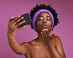 Selfie, love and black woman blowing a kiss isolated on a purple background in studio. Care, beauty and African girl with a photo, video call or communication on a mobile while showing affection