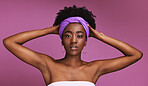 Portrait, beauty and hair with a model black woman on a pink background in studio for natural care. Face, skincare and headband with an attractive young female posing to promote cosmetic treatment